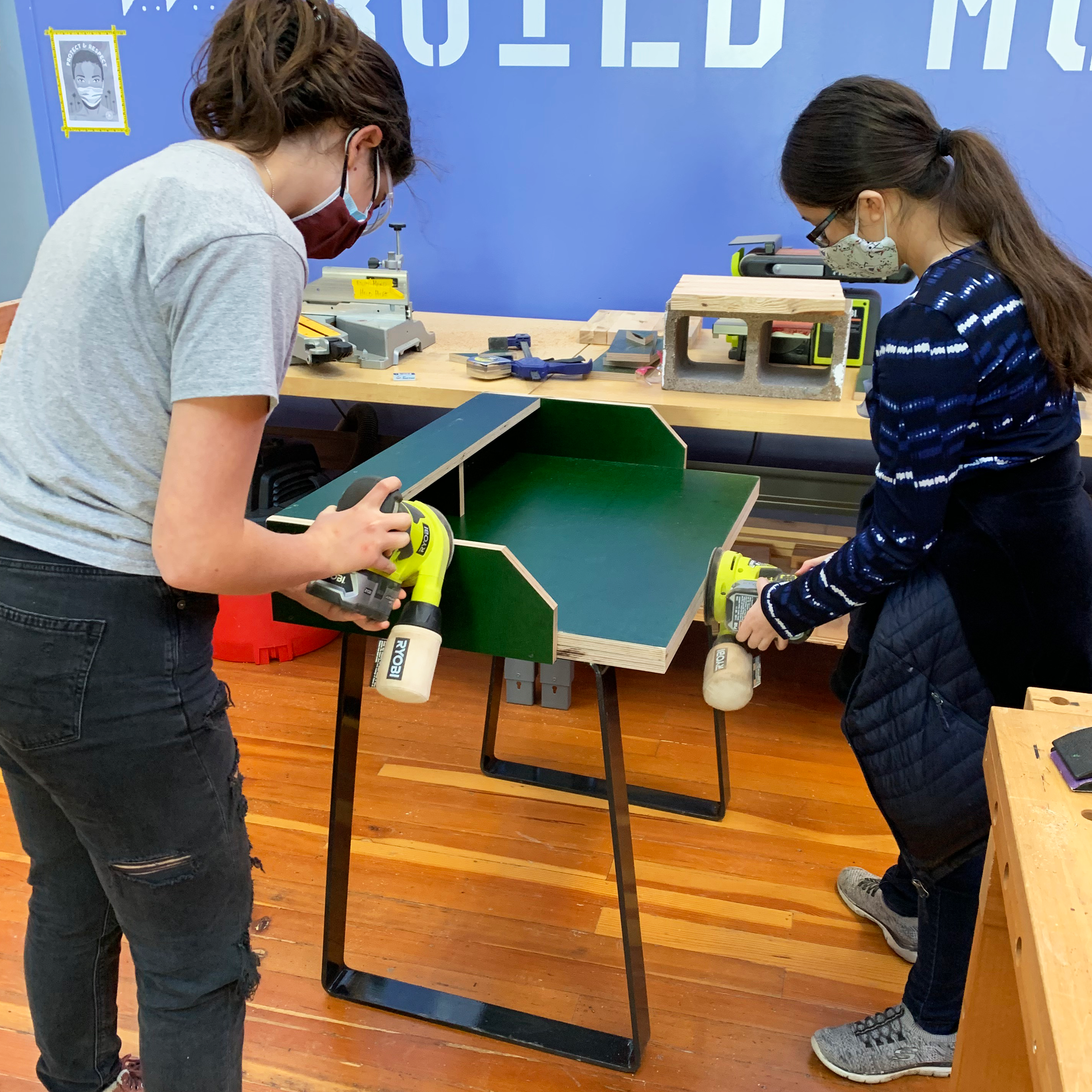 Girls Garage teen girls sand the edges of the distance learning desk