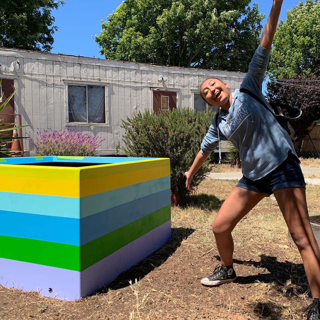 Teen artist in front of garden mural