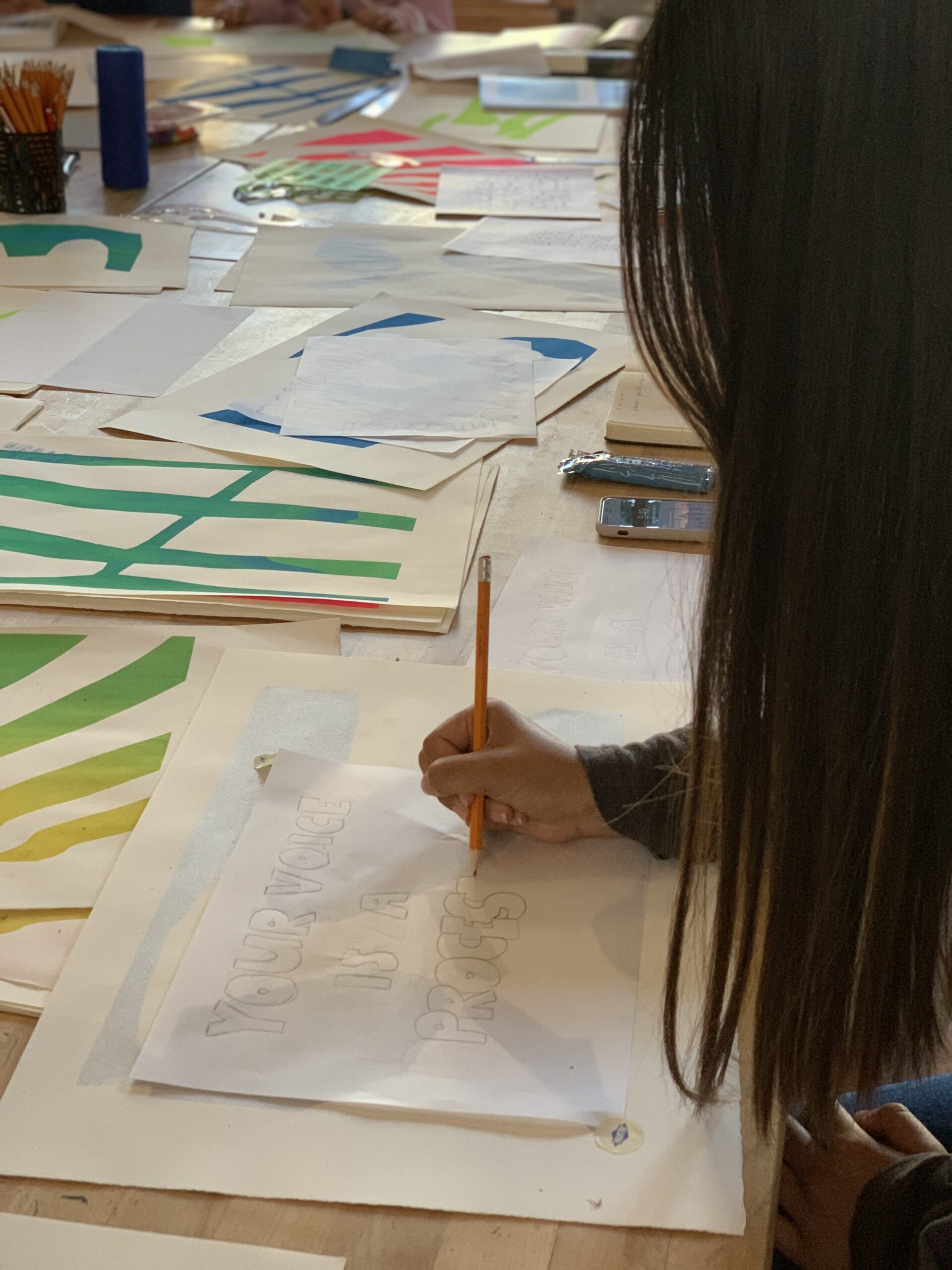 Student drafts text on carbon paper for linoleum carving project